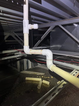 PVC condensate drain lines routed through a commercial ceiling space