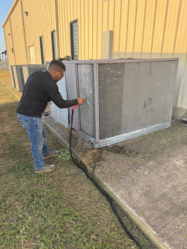 Technician washing the coil of a commercial condensing unit