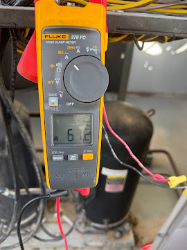 Clamp meter reading amperage on a compressor during a diagnostic check